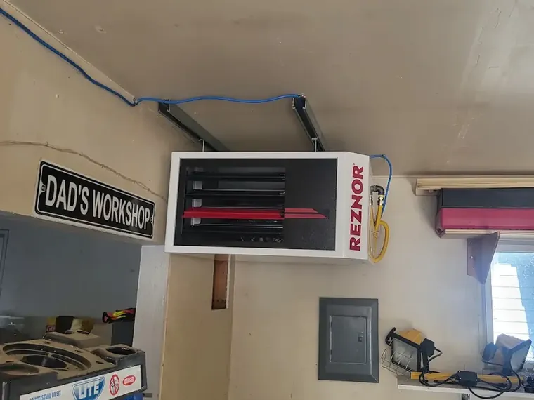 A gas unit heater hung from the ceiling of a home workshop