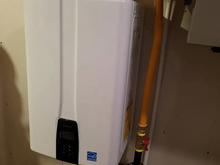 A wall-mounted tankless water heater with a yellow gas line running up beside it