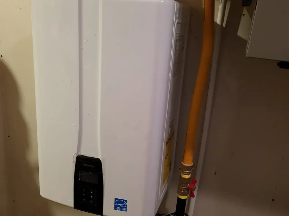 A wall-mounted tankless water heater with a yellow gas line running up beside it